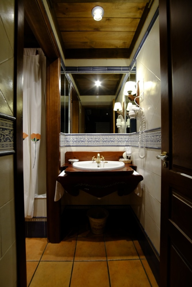 Baño con molduras de madera oscura, tocador y espejo grande. Ducha con cortina a la izquierda.