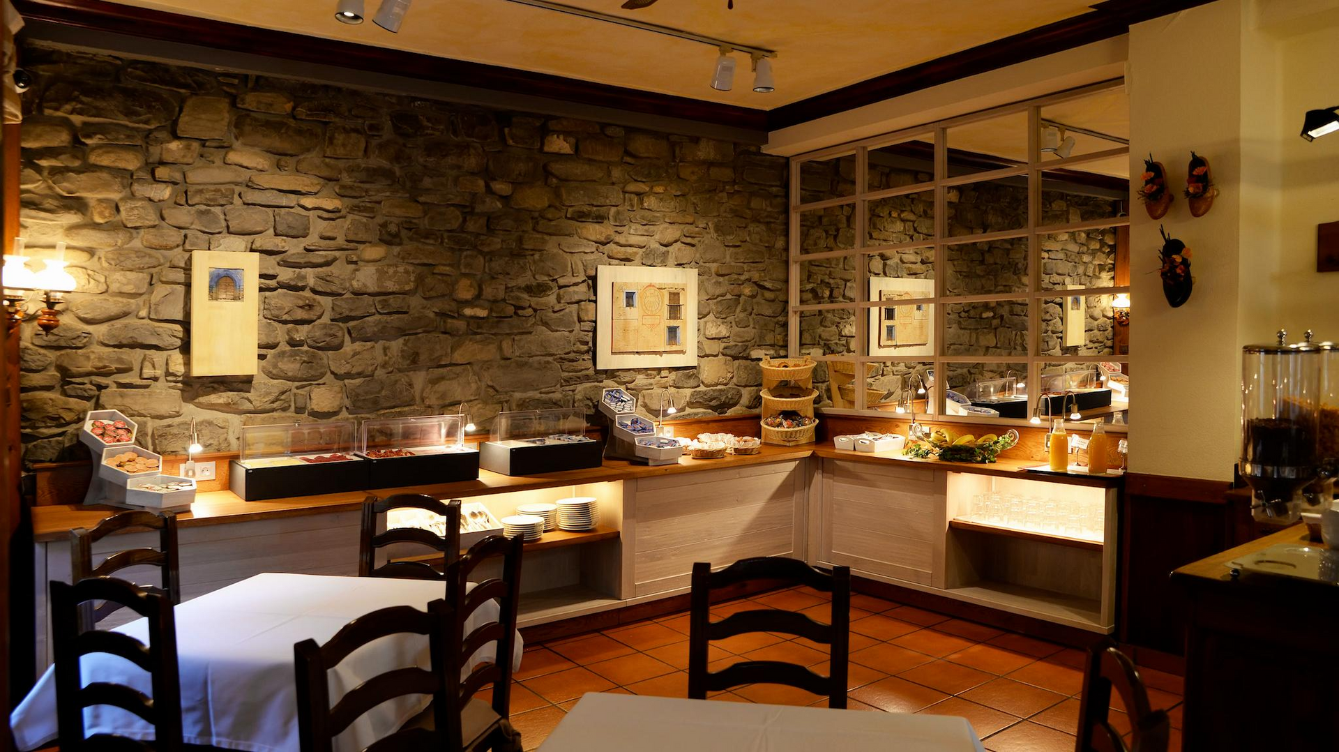 Comedor de restaurante con pared de piedra, buffet y mesas.