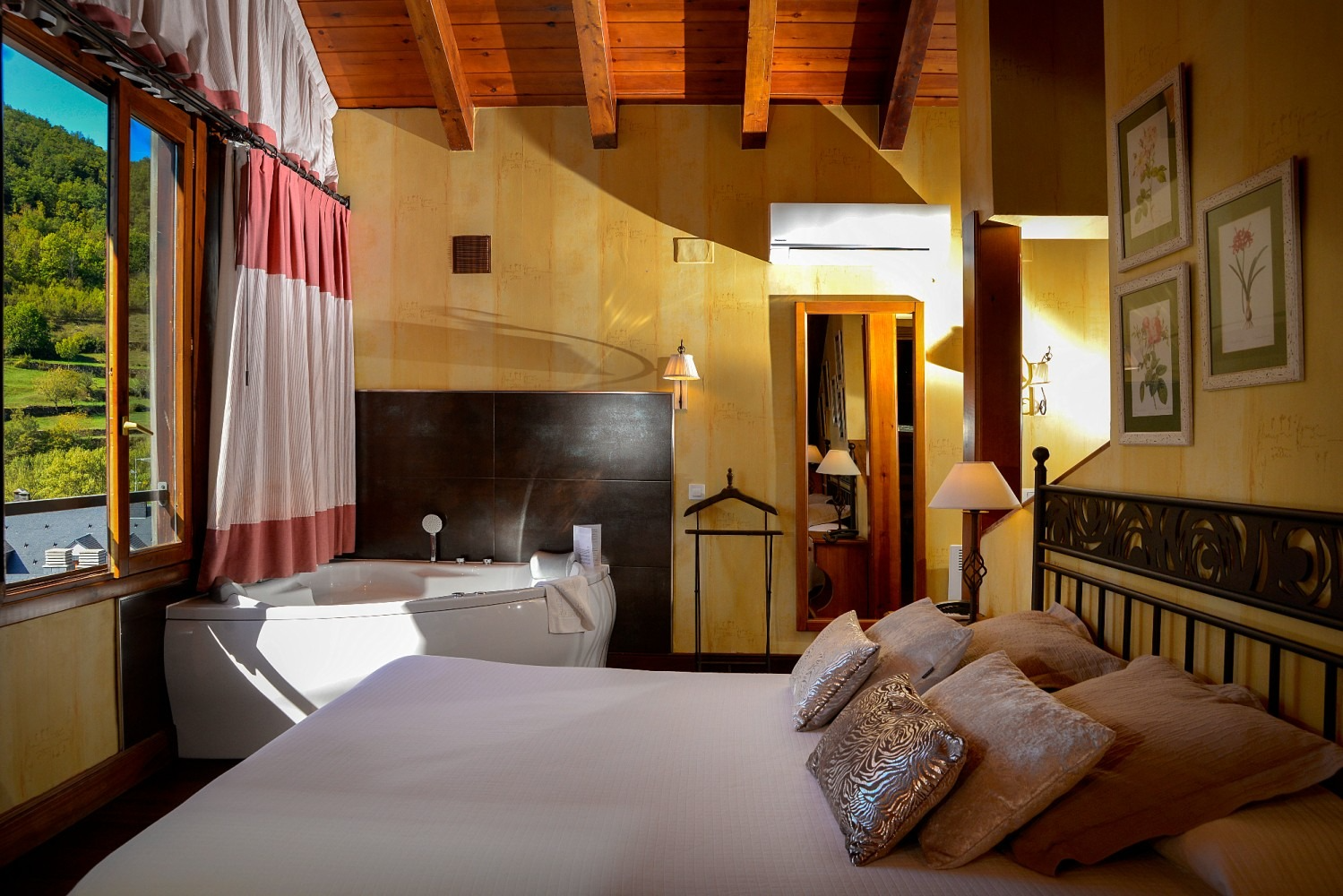 Acogedora habitación con cama, jacuzzi y vista a la montaña desde una ventana. Techo de madera e iluminación cálida.