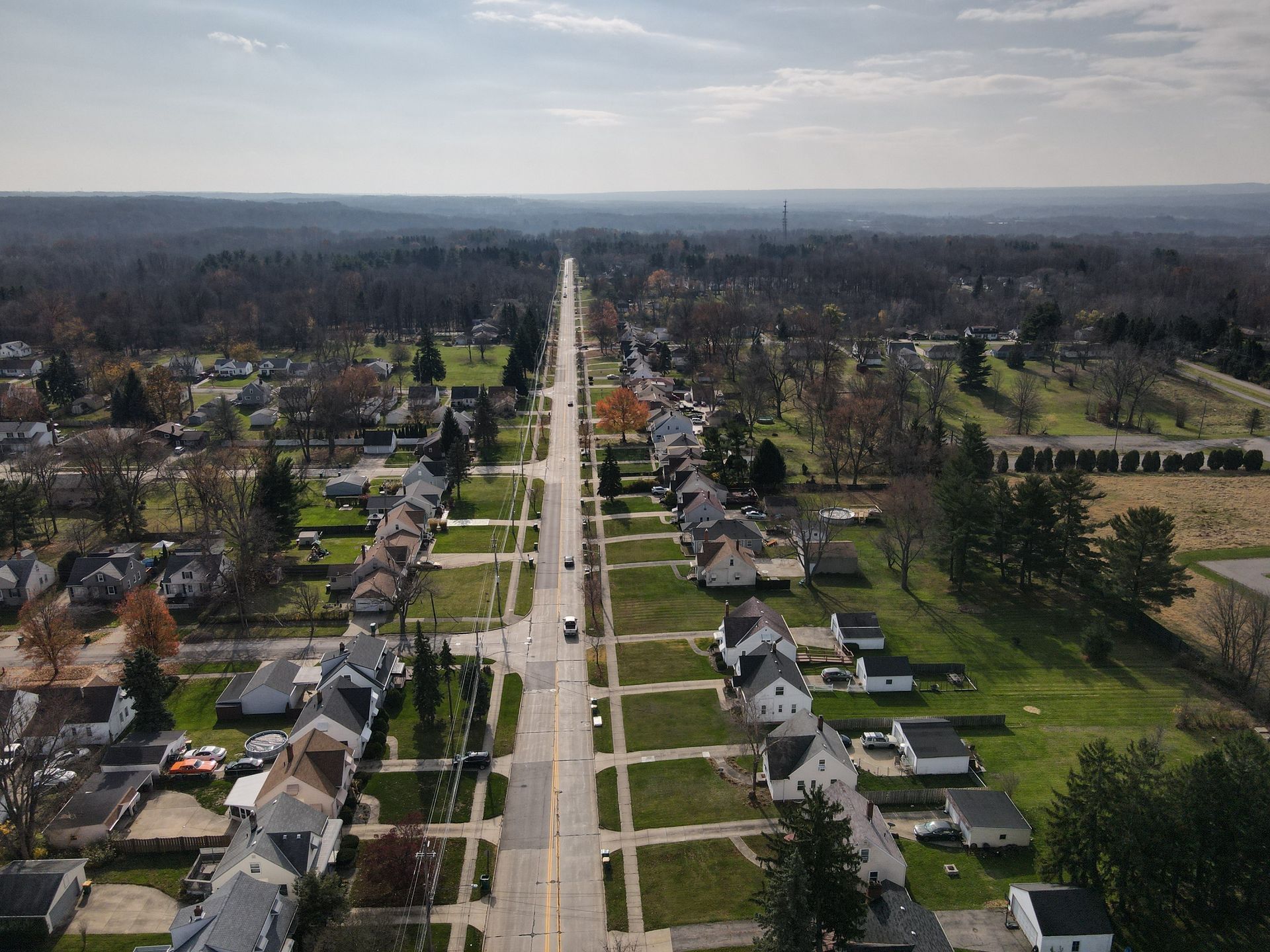 An aerial view of a residential area with a long road going through it.