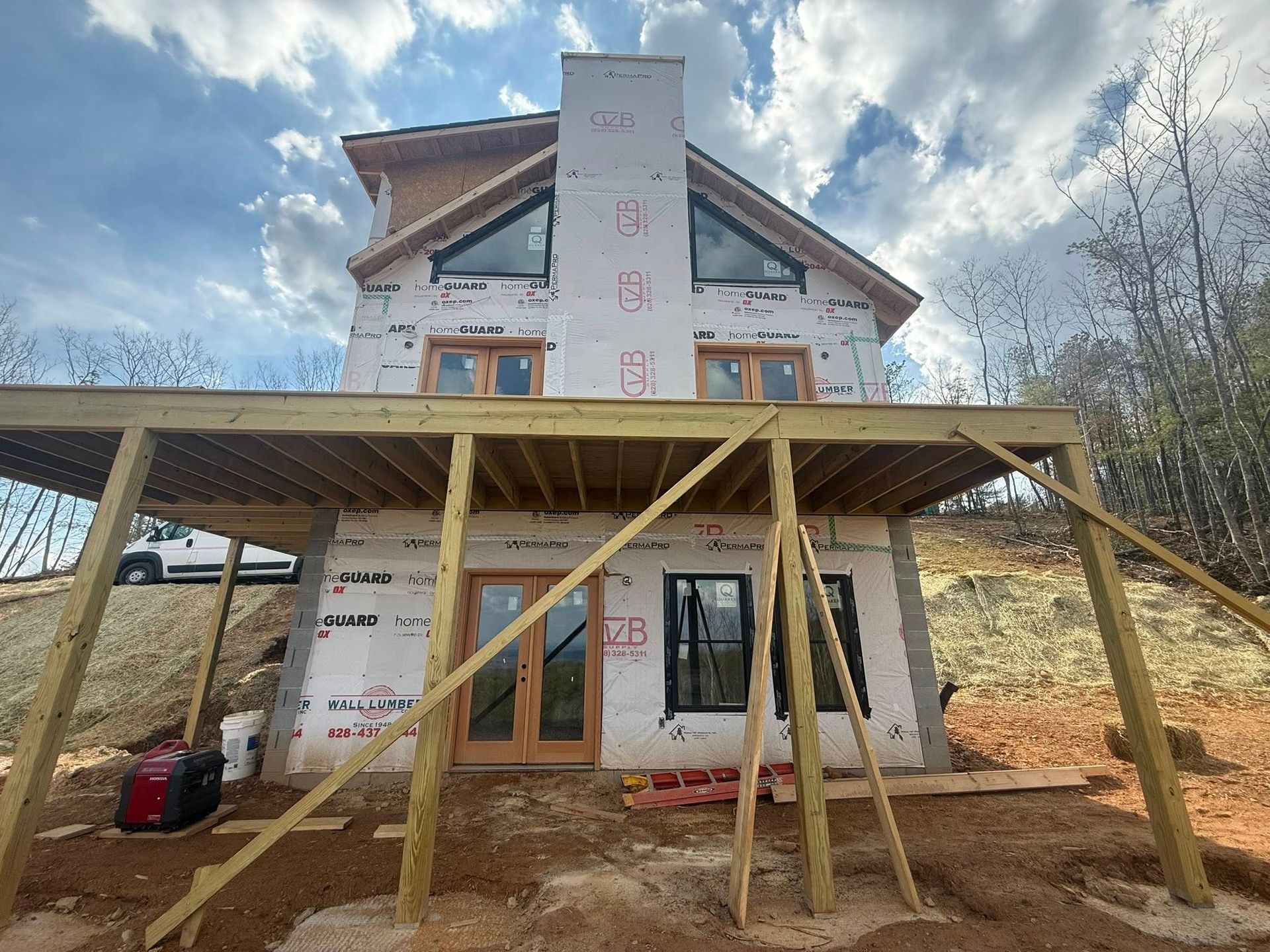 Partially built house with wood-framed porch and roof under construction on a hillside