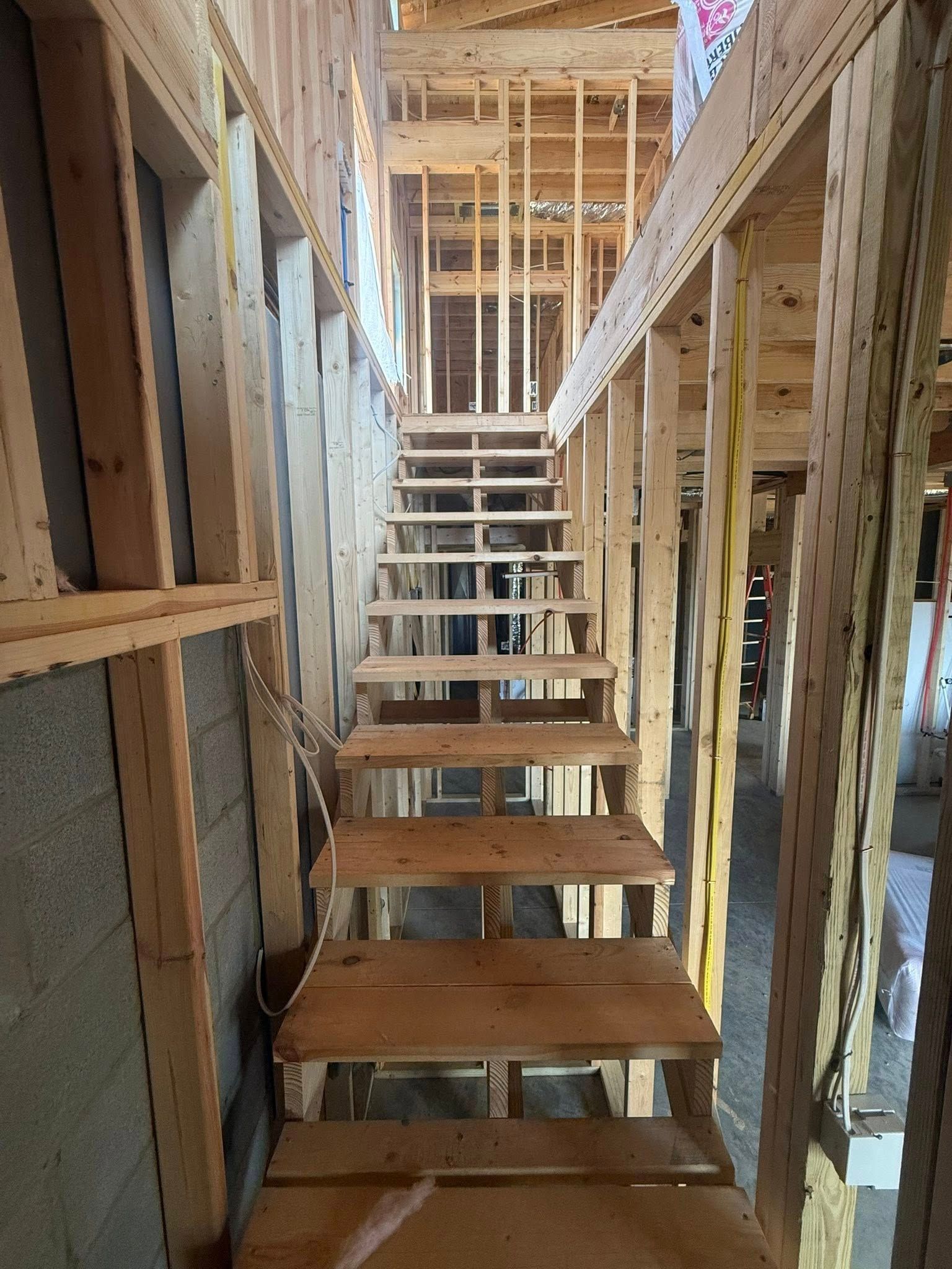 Unfinished wooden staircase in a narrow framed house interior under construction