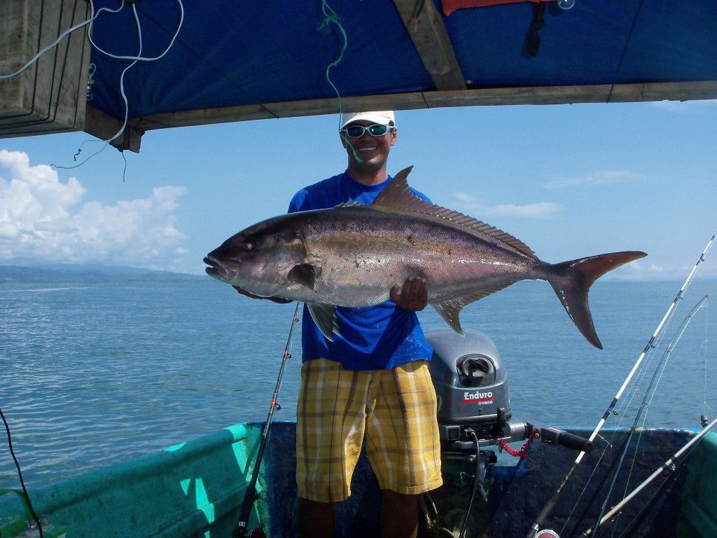 A man on a boat holding a large fish