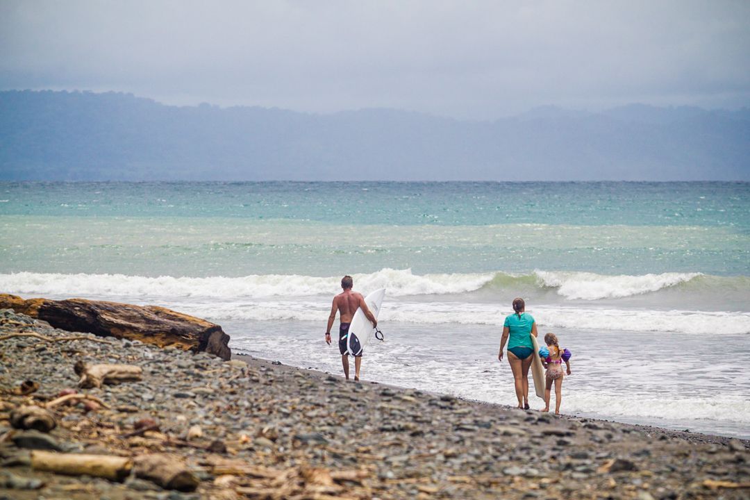 A family is walking on the beach near the ocean.