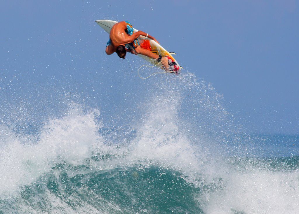 A surfer is flying through the air while riding a wave