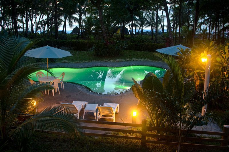 A swimming pool is lit up at night with green lights