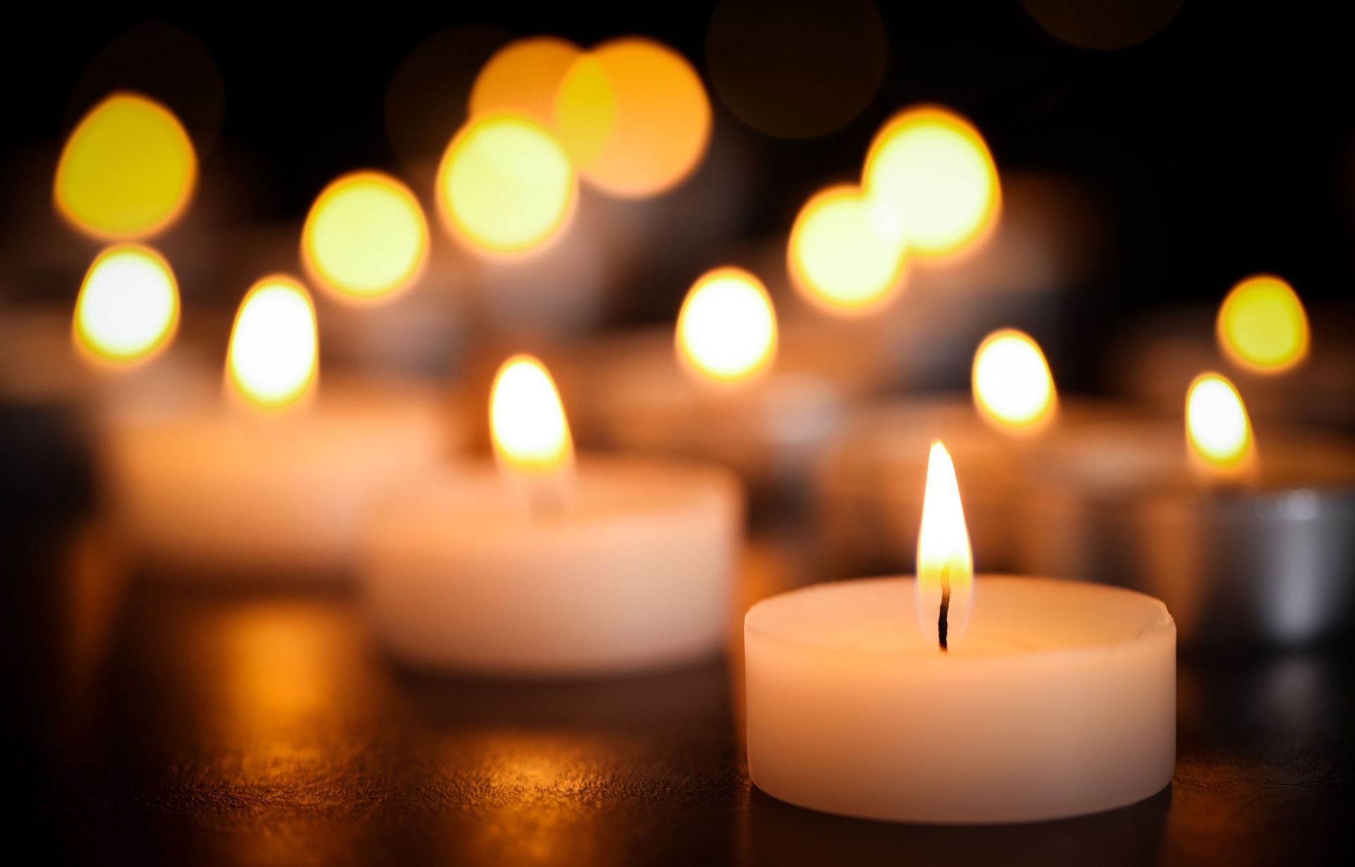 A group of lit candles are sitting on a table.
