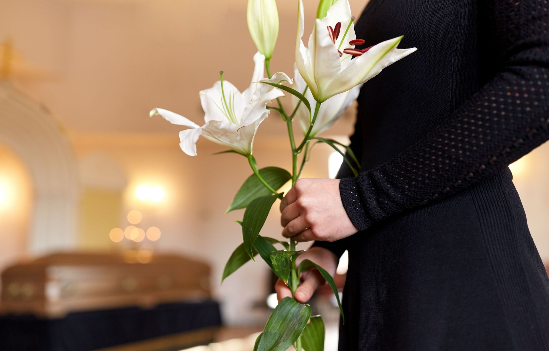 A woman in a black dress is holding a bouquet of white flowers.