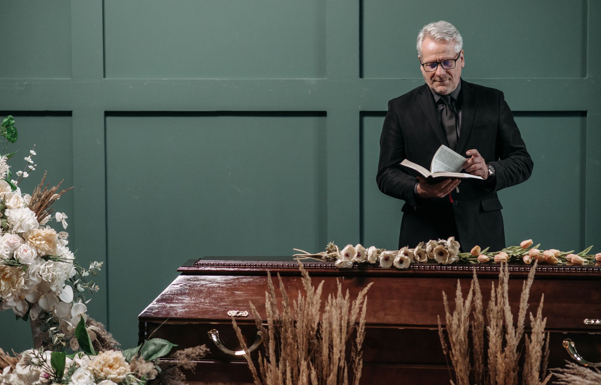 A man is standing in front of a coffin at a funeral.