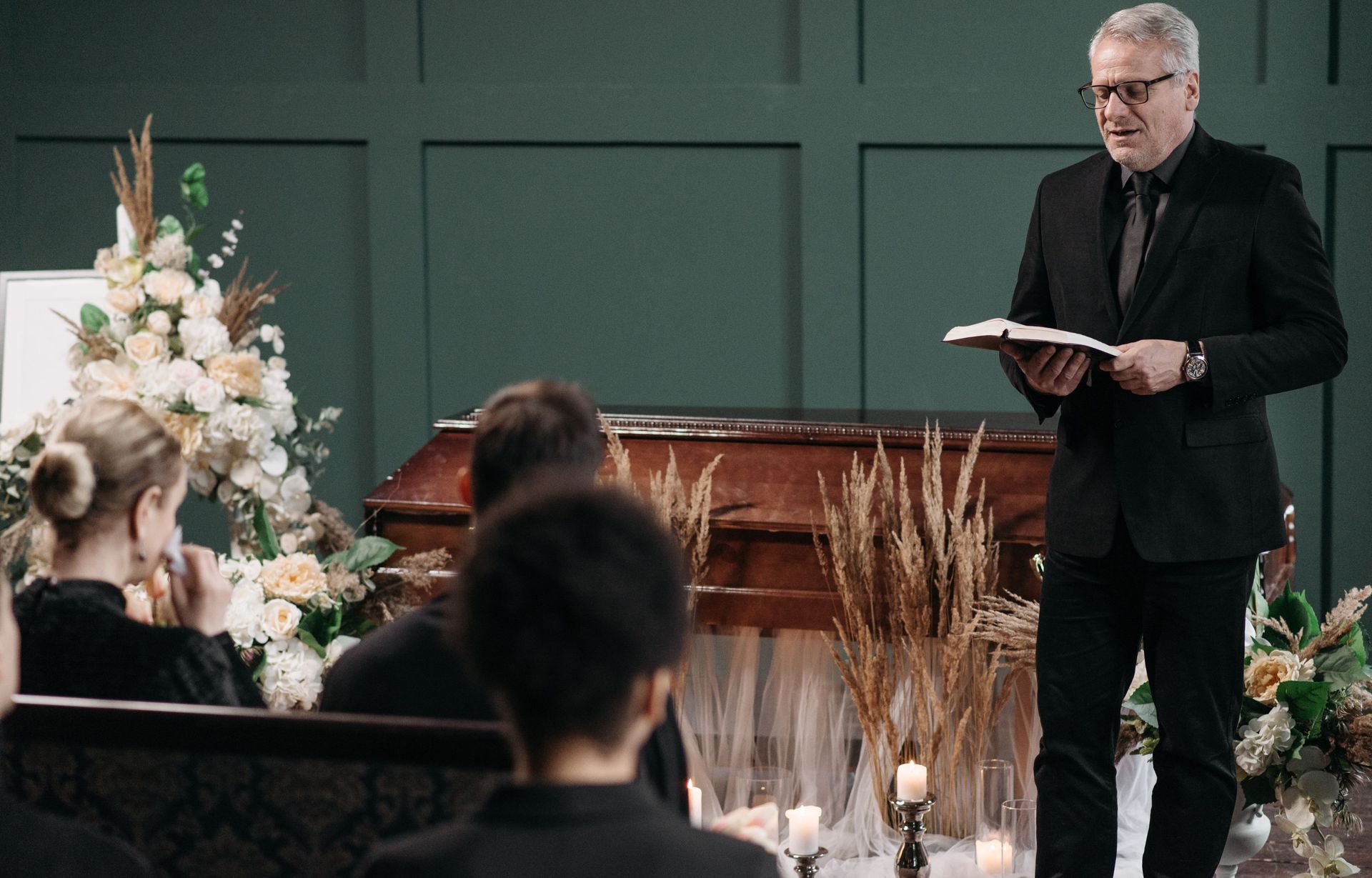 A man in a suit is giving a speech at a funeral.