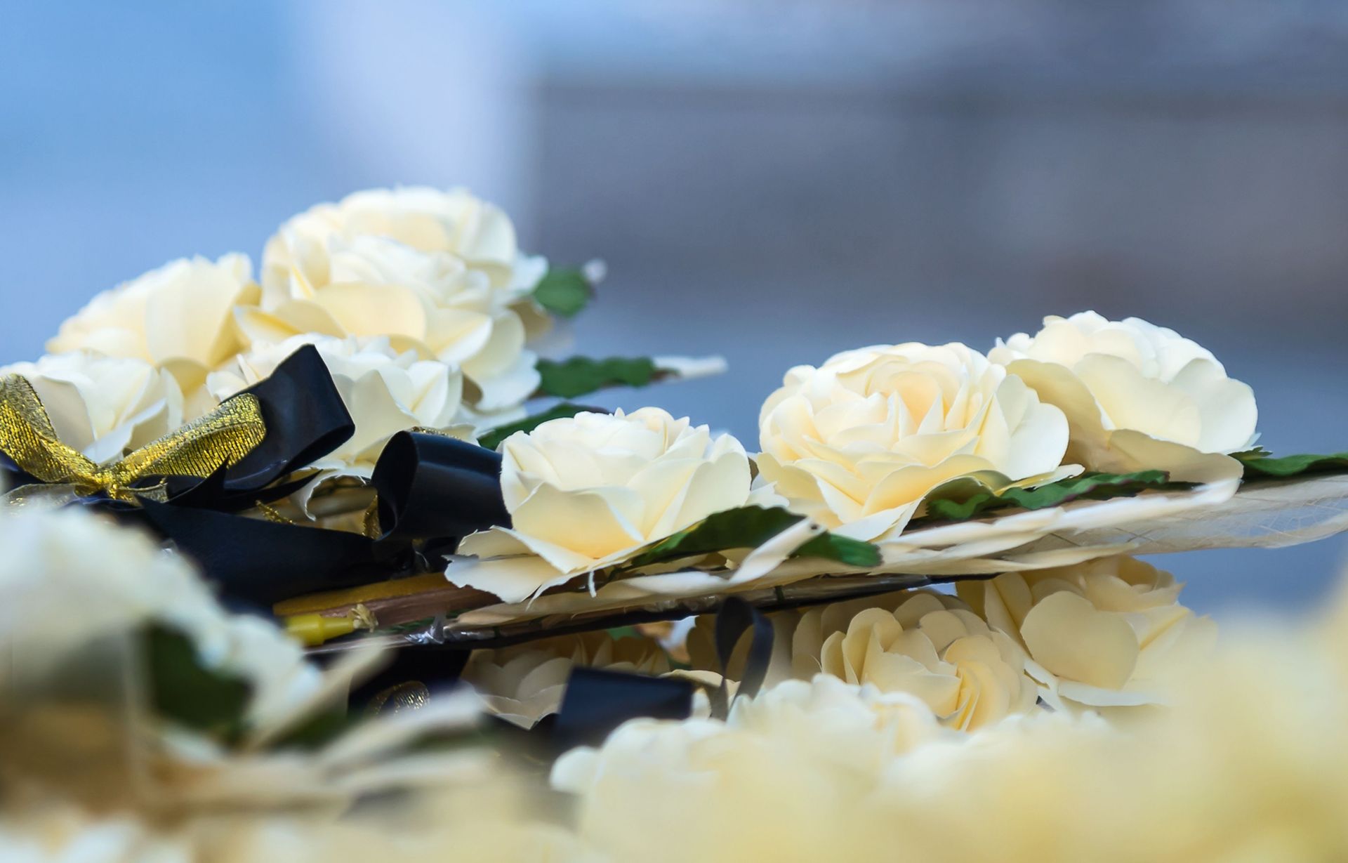 A bunch of white roses with a black ribbon on a table.