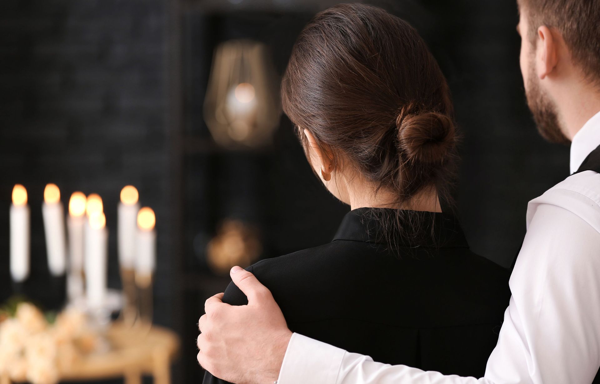 A man is hugging a woman at a funeral.