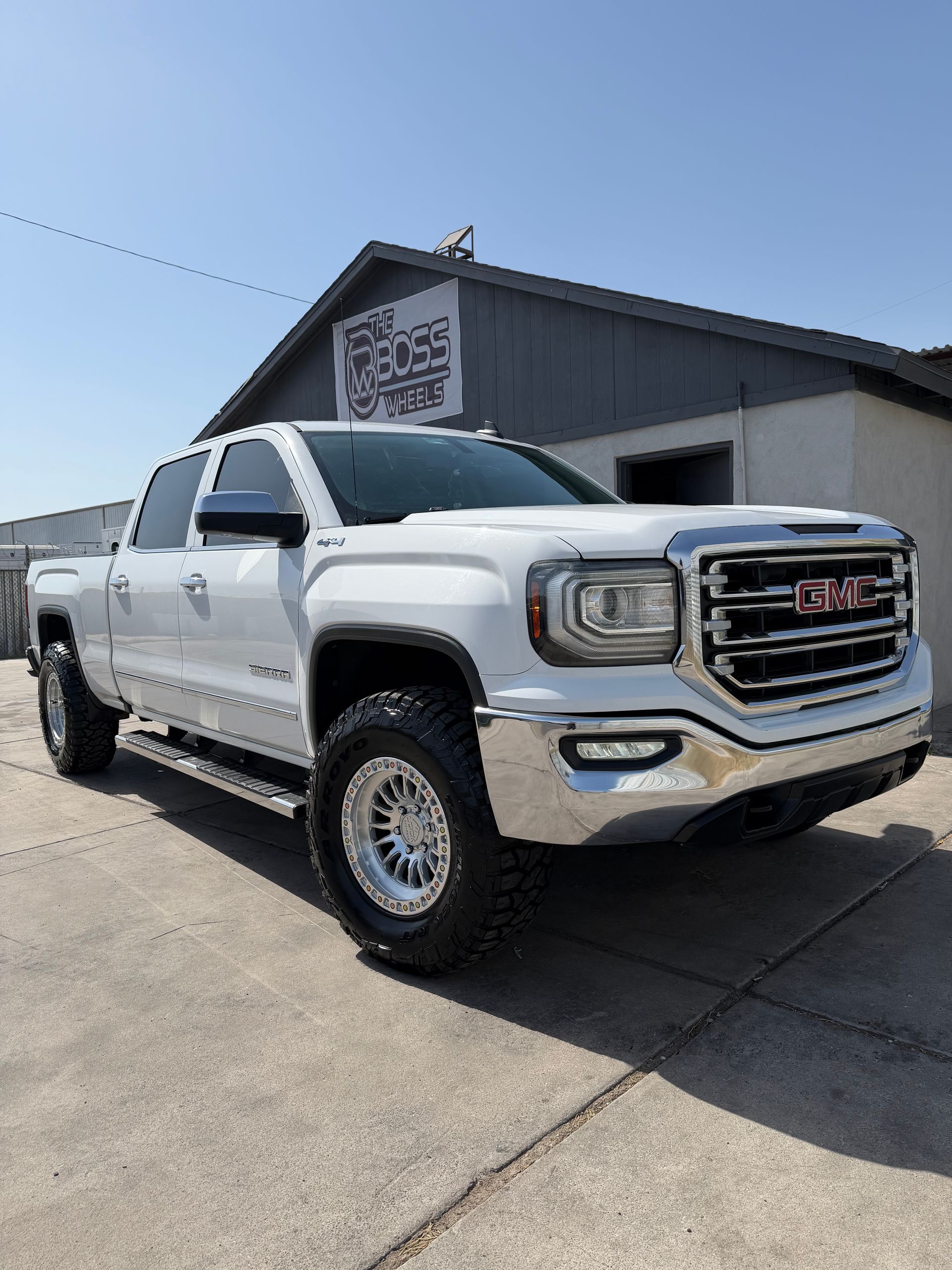 White GMC pickup truck parked outside a building on a sunny day