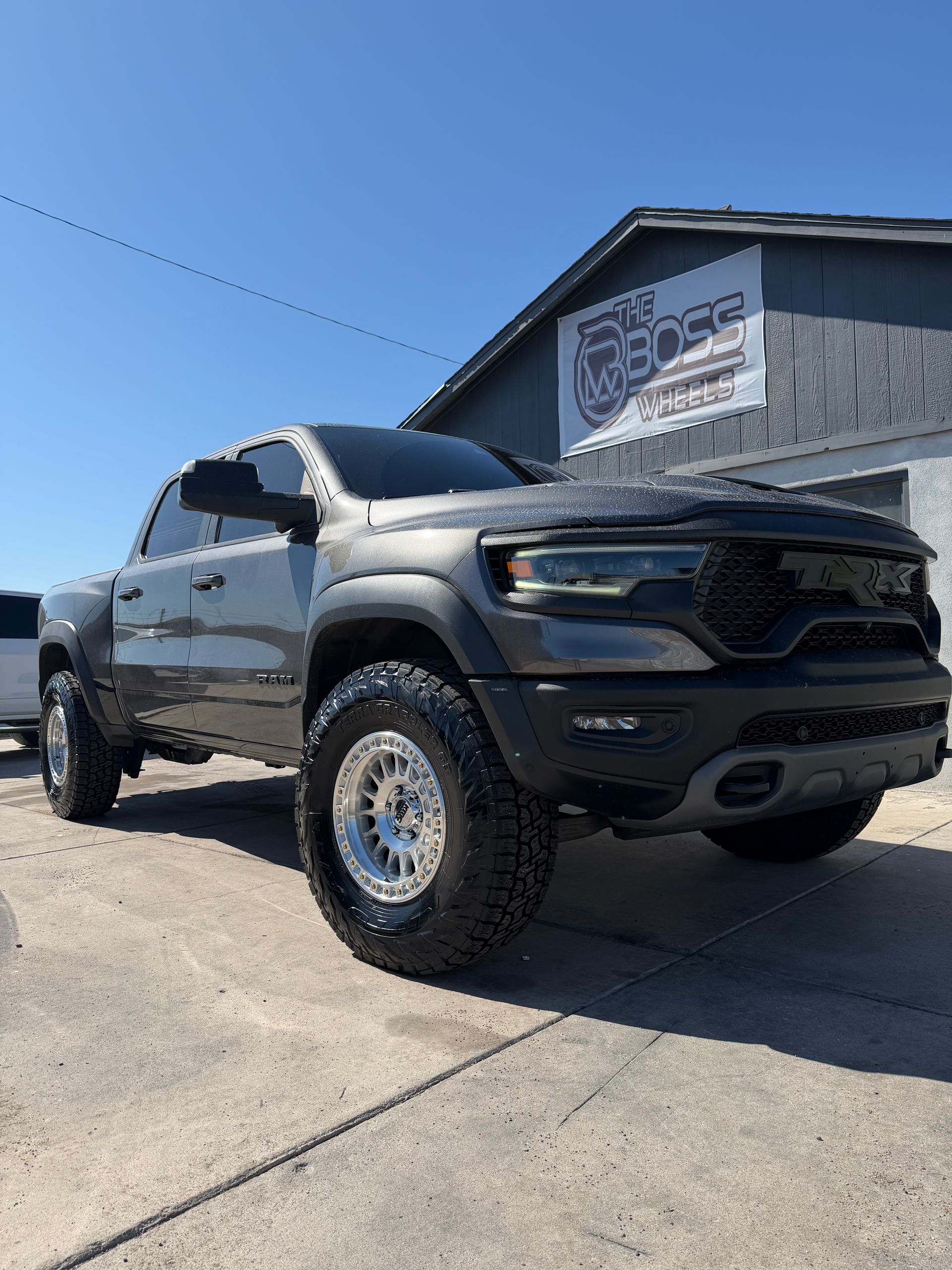 Gray lifted pickup truck parked outside a building on a sunny day