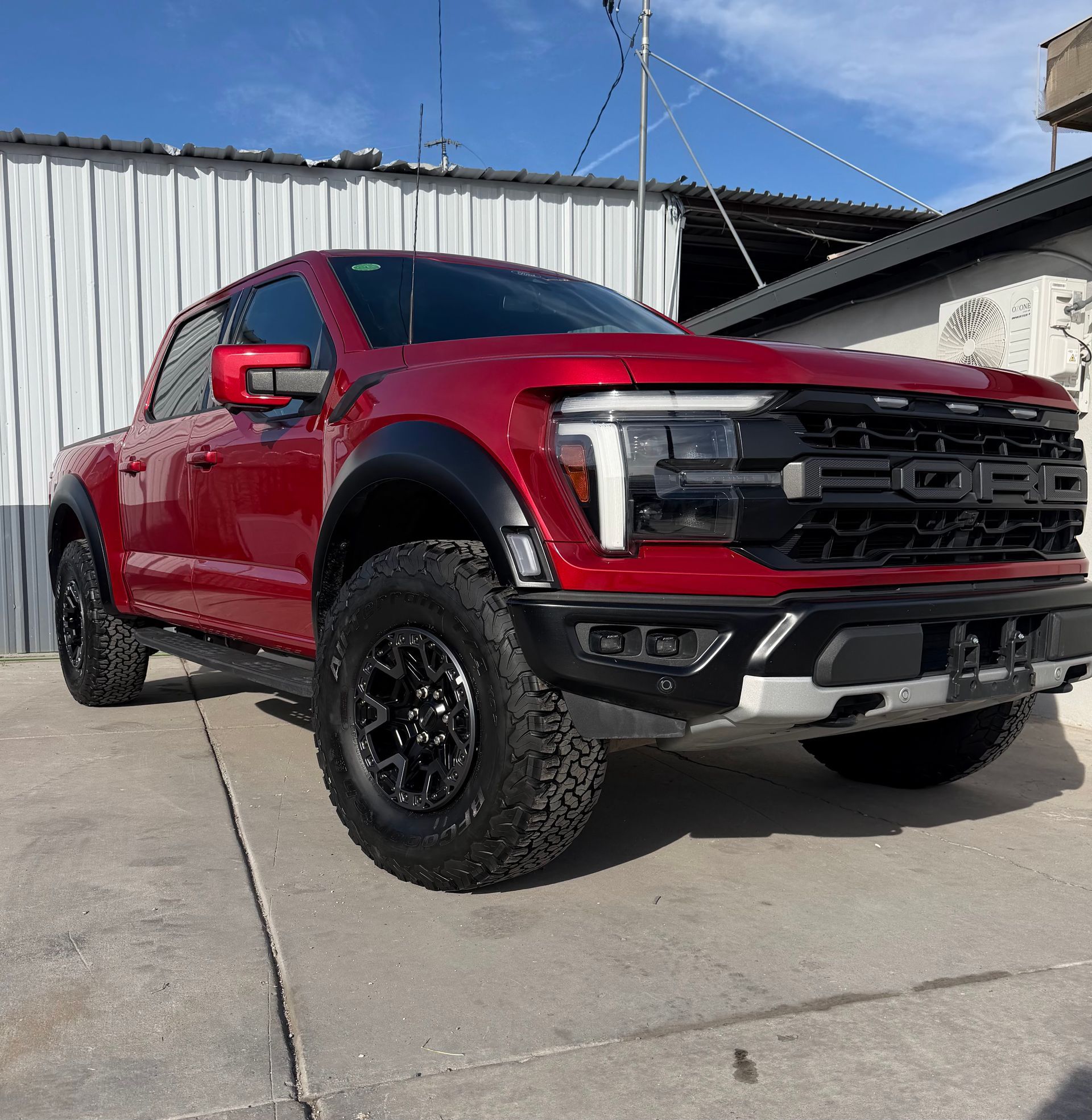 Red Ford pickup truck parked outdoors on a concrete lot, front three-quarter view