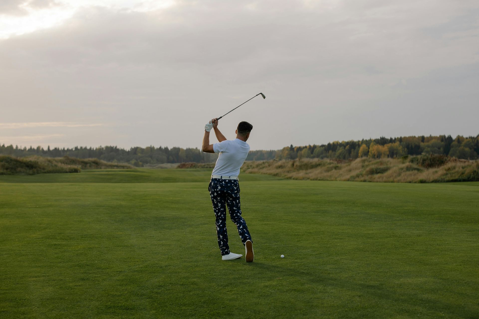 A man is swinging a golf club on a golf course.