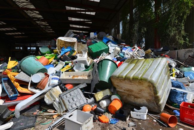 Pile of discarded plastic items, various shapes and colors, in a warehouse or shed.