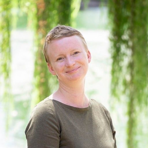 A woman in a green shirt is smiling for the camera.