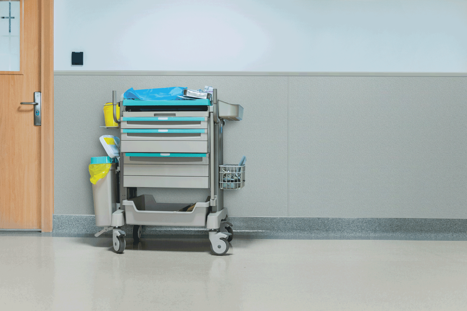 A hospital cart is sitting in a hallway next to a door.