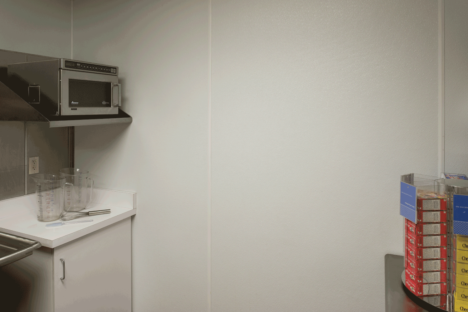 A kitchen with a microwave and boxes of cereal on the counter.