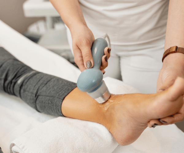 Foot massage with a handheld massage device on a person’s ankle in a spa setting