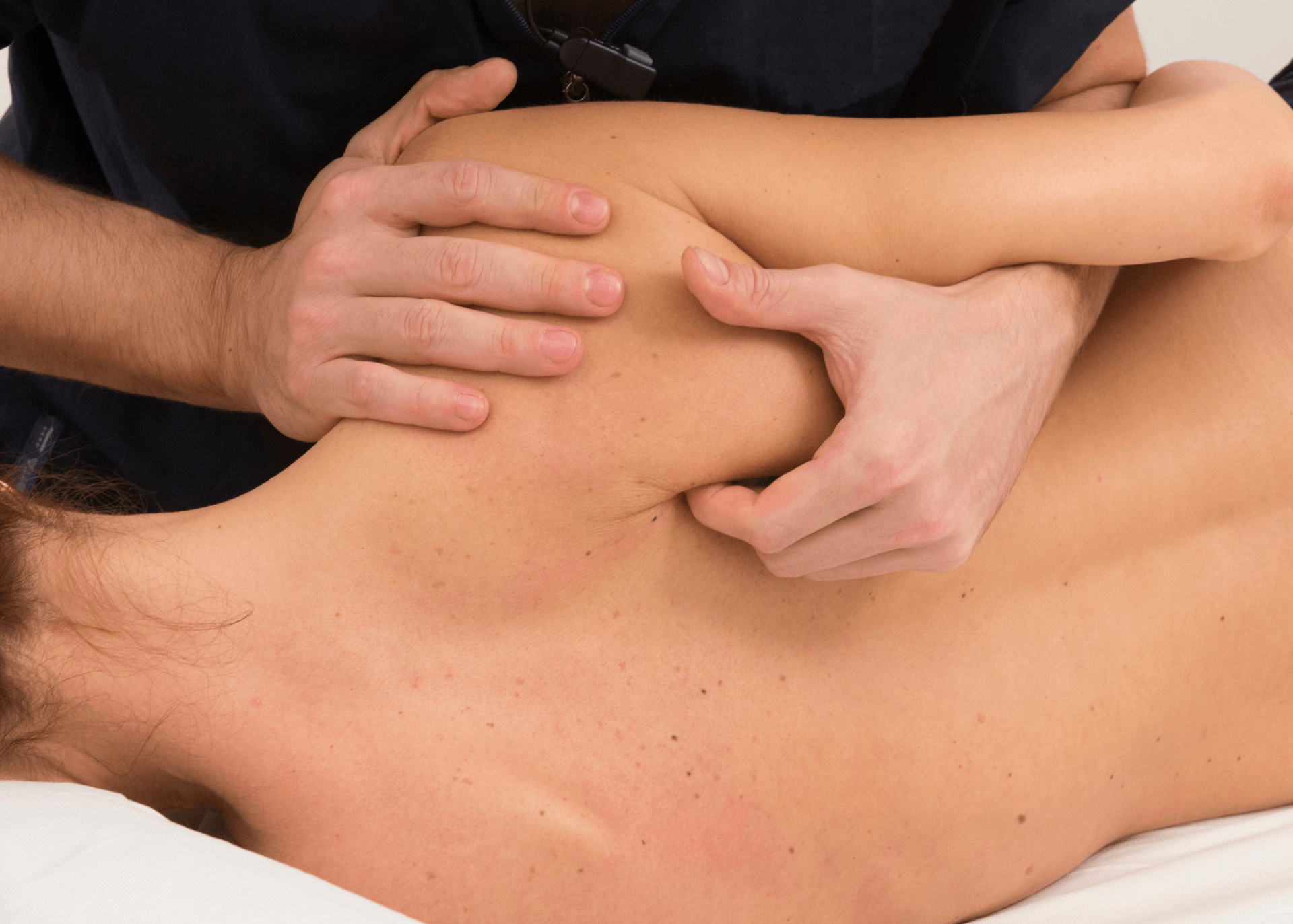 Hands giving a shoulder massage to a person lying face down on a table