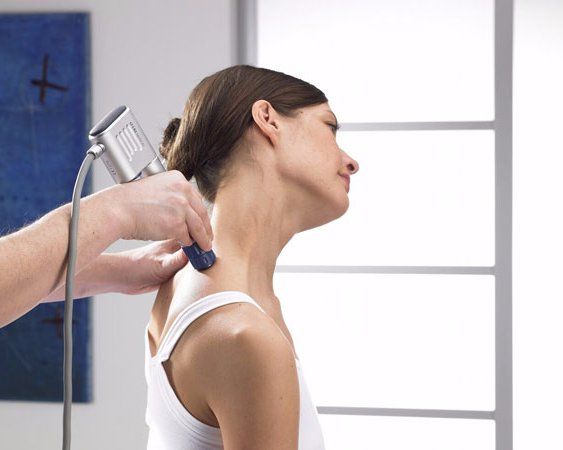 Person receiving a neck treatment with a handheld device in a bright clinical room
