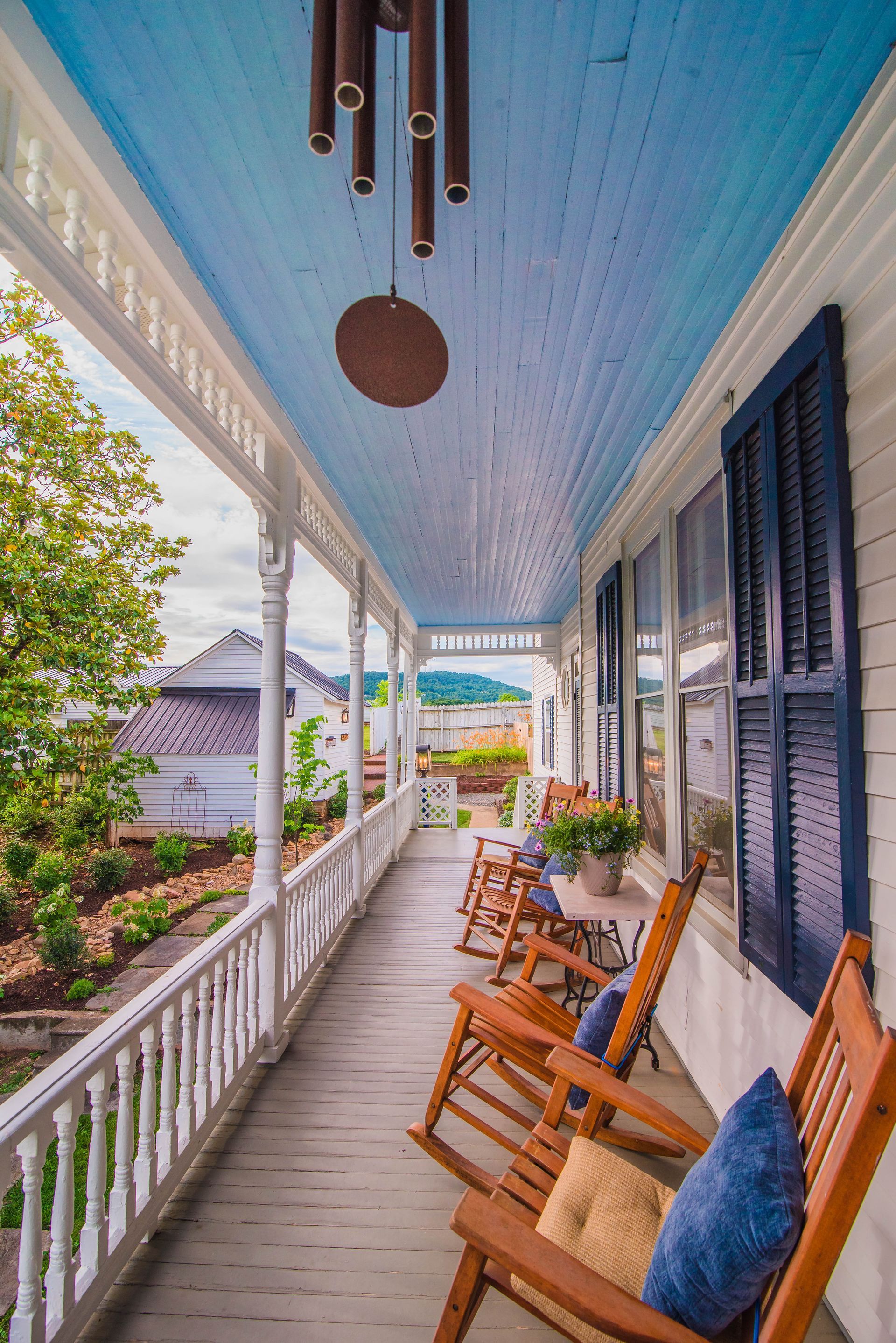 A porch with rocking chairs and a wind chime hanging from the ceiling.