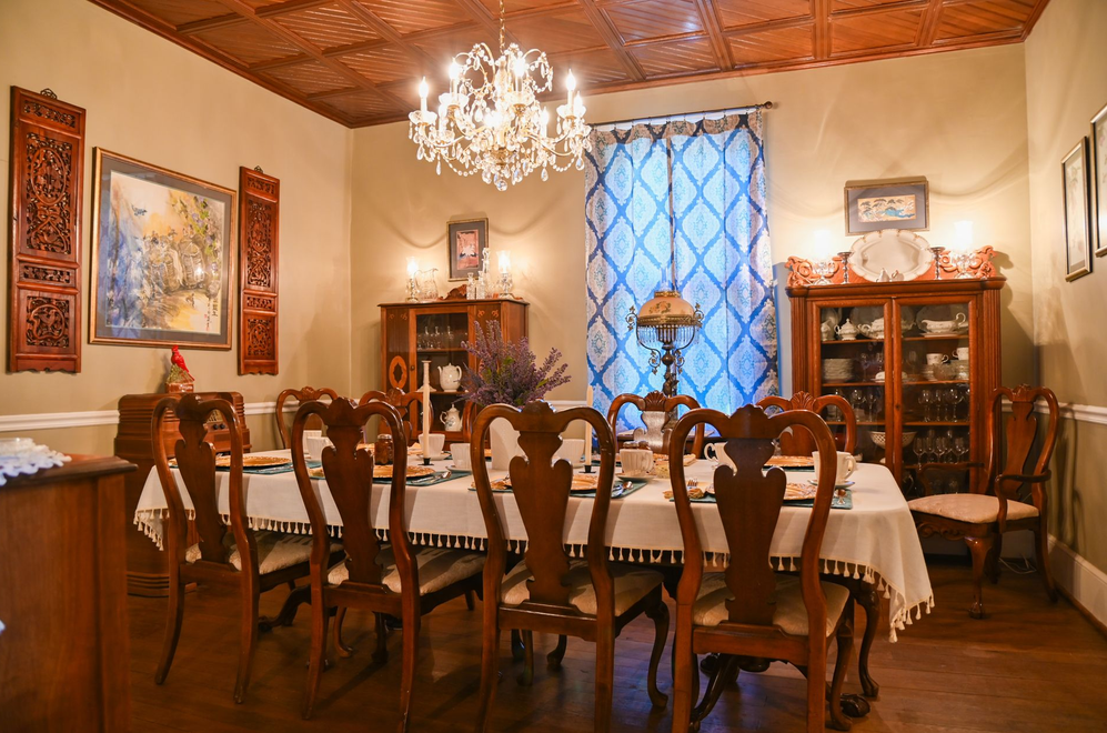 A dining room with a long table and chairs and a chandelier.
