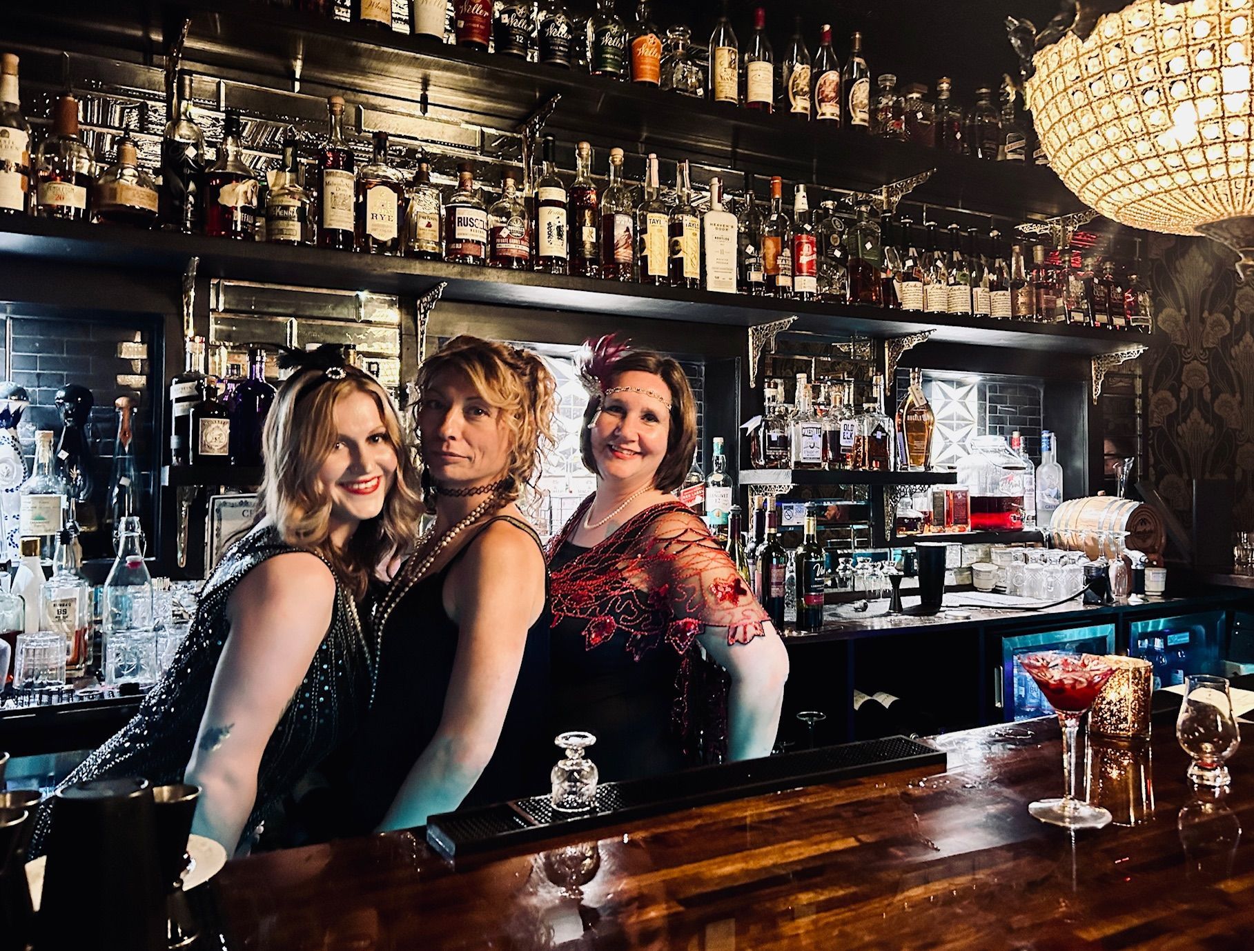 Three women are posing for a picture at a bar.