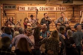 A group of people are dancing in front of a sign that says the floyd country store.