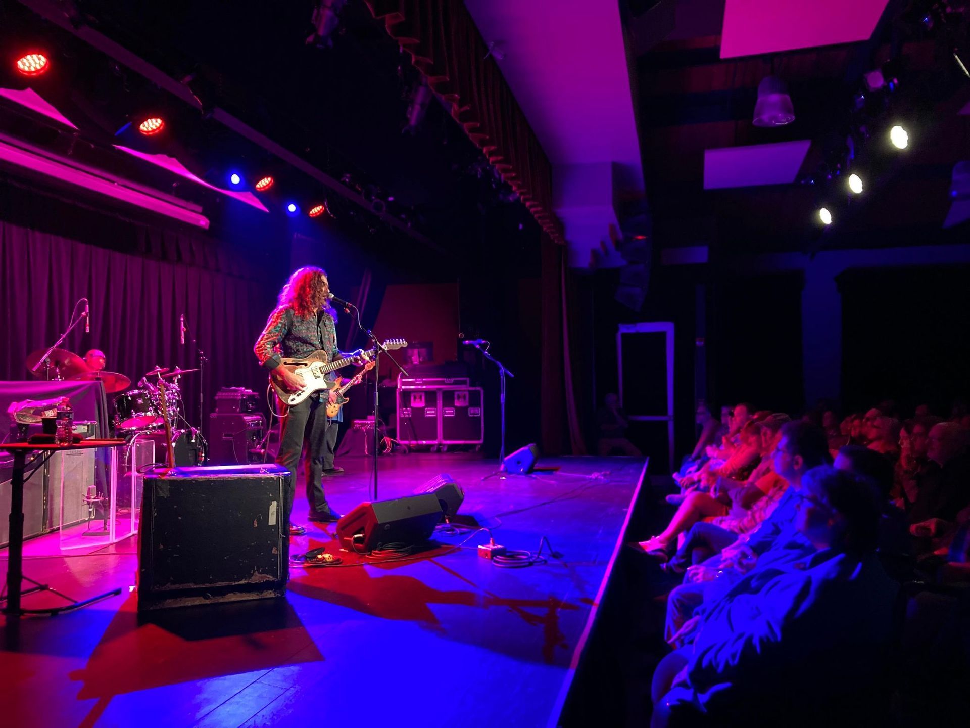 A man is playing a guitar on a stage in front of a crowd.