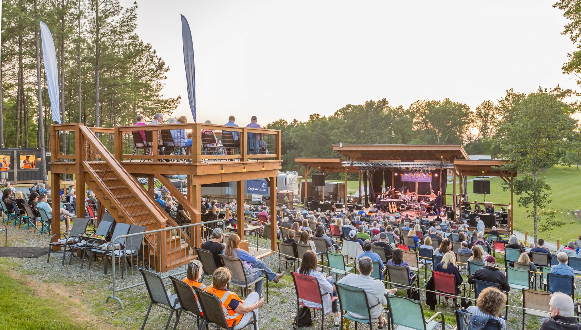 A large group of people are sitting in chairs in front of a stage watching a concert.