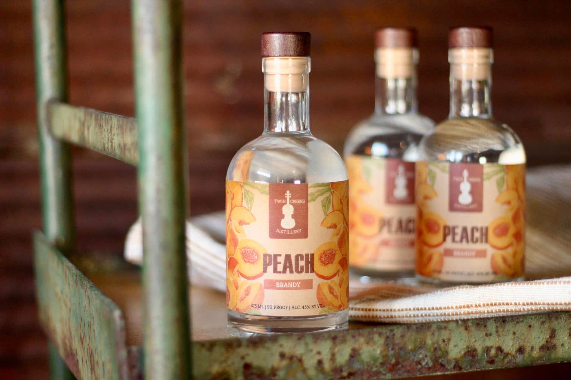Three bottles of peach vodka are sitting on a table.