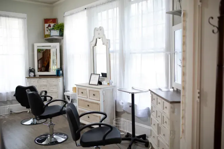 A hair salon with two chairs and a mirror.
