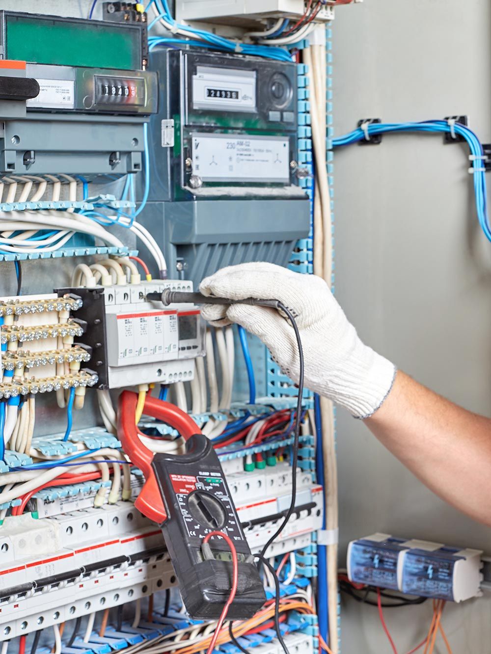 Elettricista che testa il cablaggio all'interno di un quadro elettrico aperto con sonde multimetro.