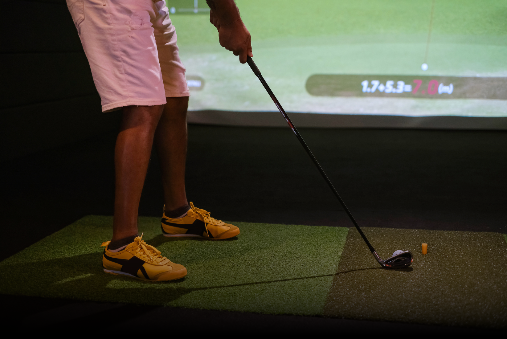 A man is playing golf in an indoor simulator at Golfbiz