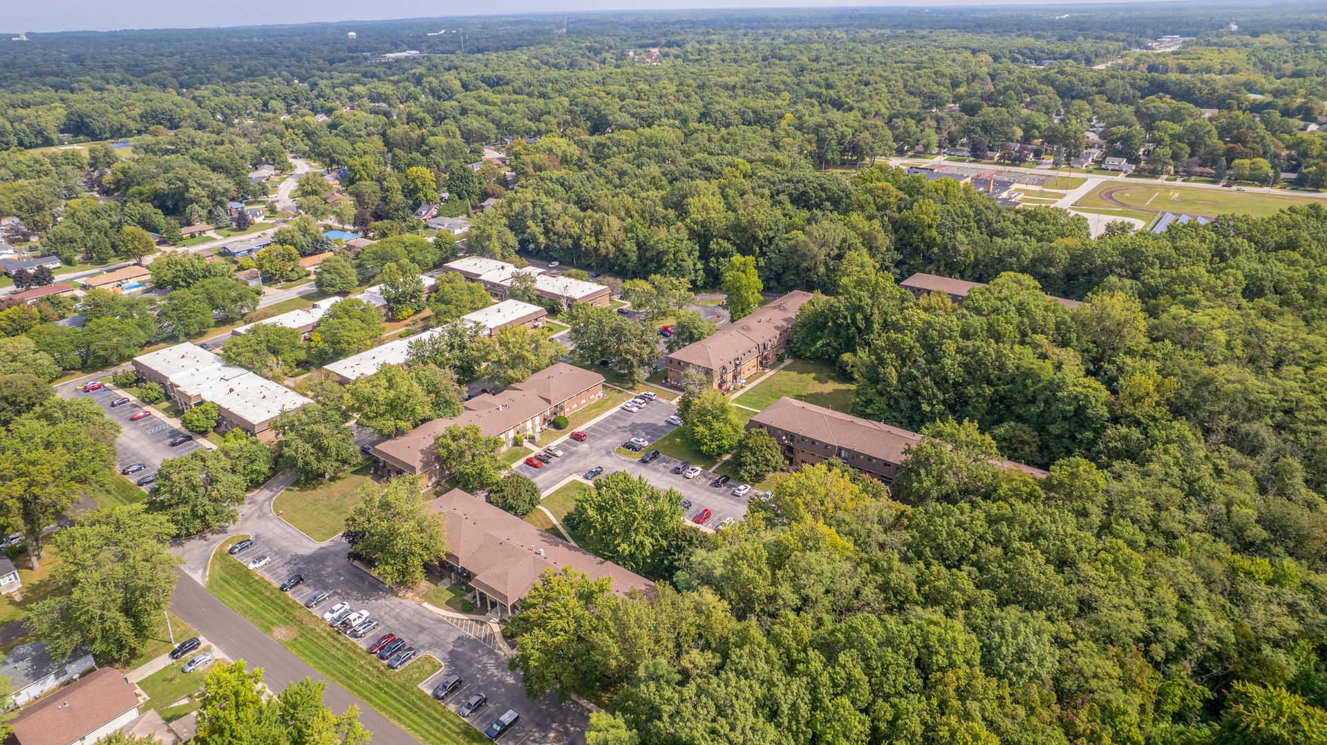 Aerial view of apartment buildings surrounded by lush green trees.