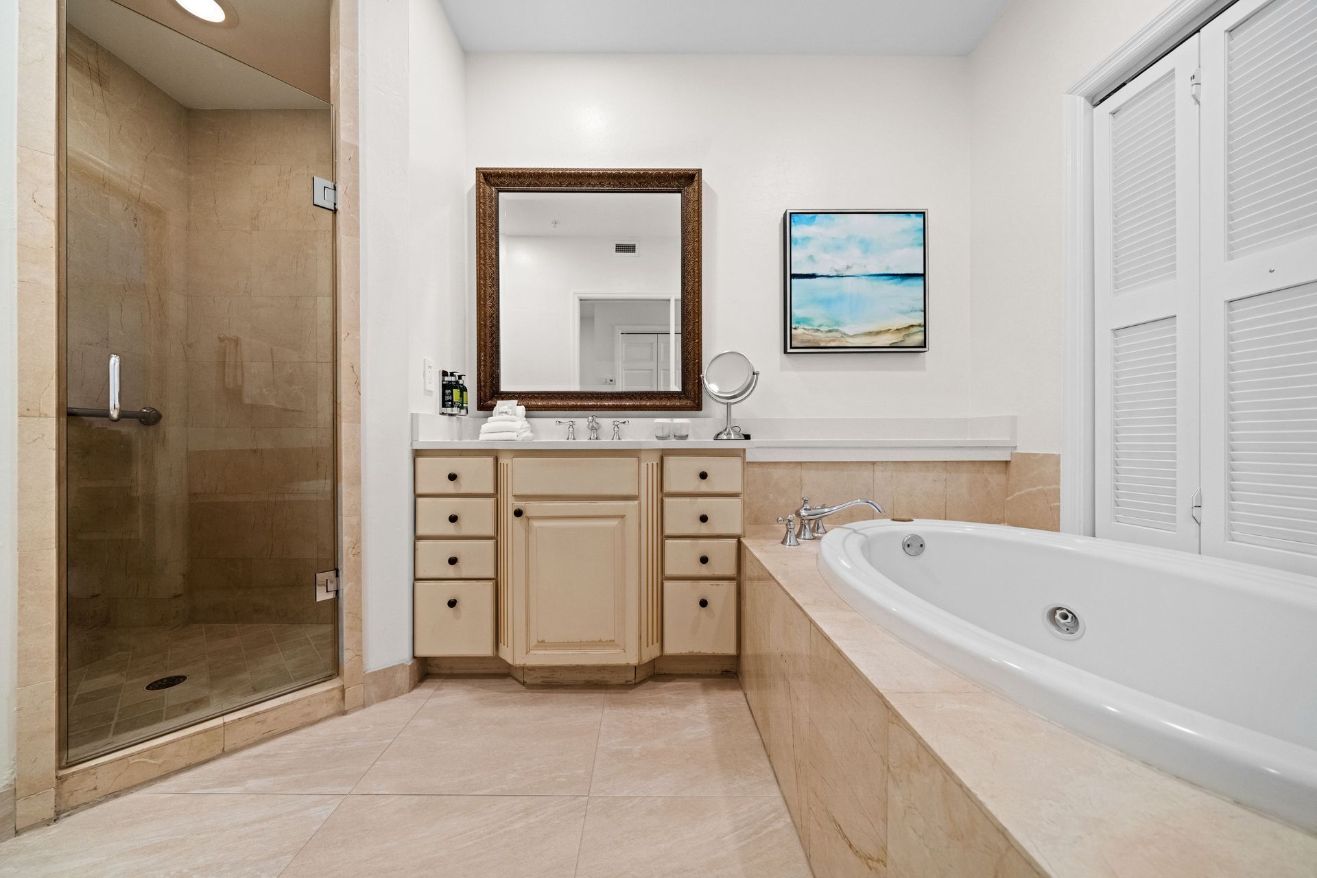 Spacious beige bathroom with glass shower, double vanity, soaking tub, and a wall mirror.