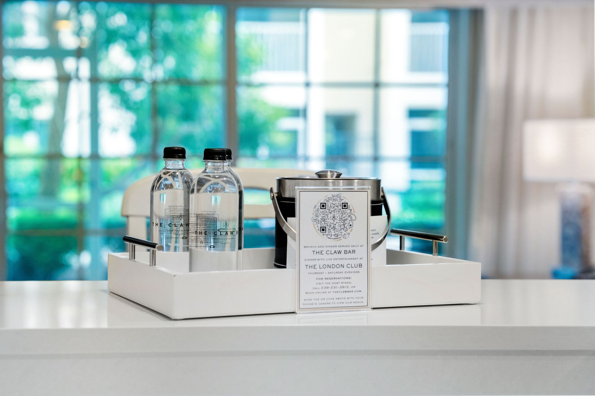 Gift set with bottled drinks and a card on a white tray in a bright room