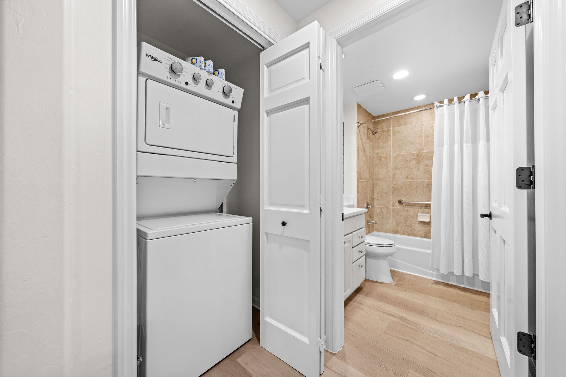 Laundry closet with stacked washer and dryer in a bright bathroom hallway