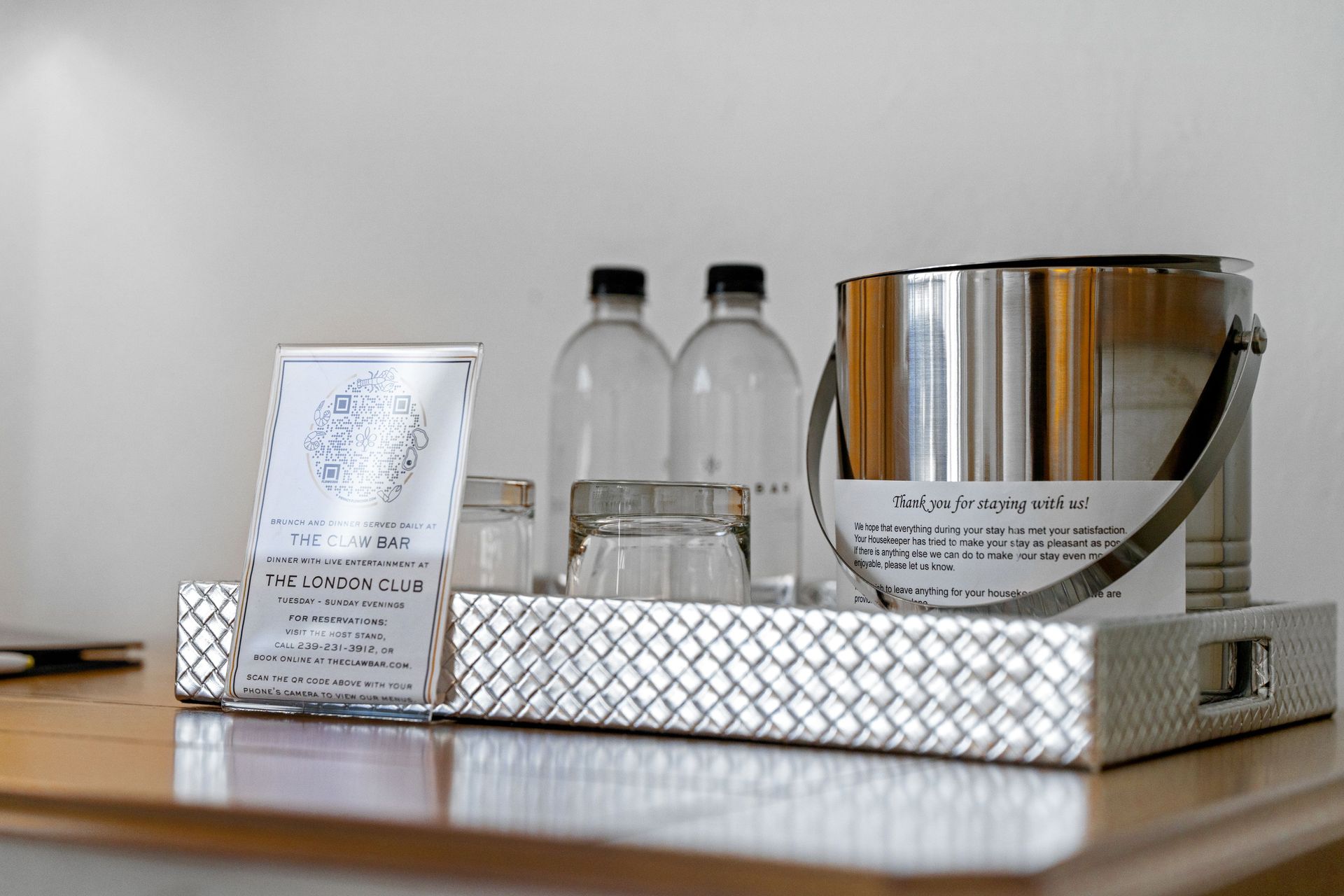 Hotel tray with bottled water, a metal ice bucket, and note cards on a table
