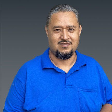 Studio portrait of a man in a bright blue polo shirt against a gray background