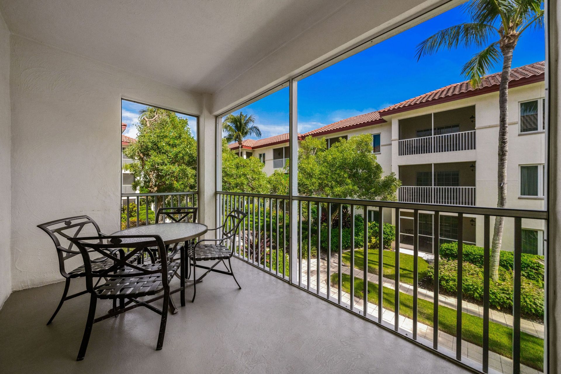 Covered balcony with patio table and chairs overlooking a courtyard and apartment buildings