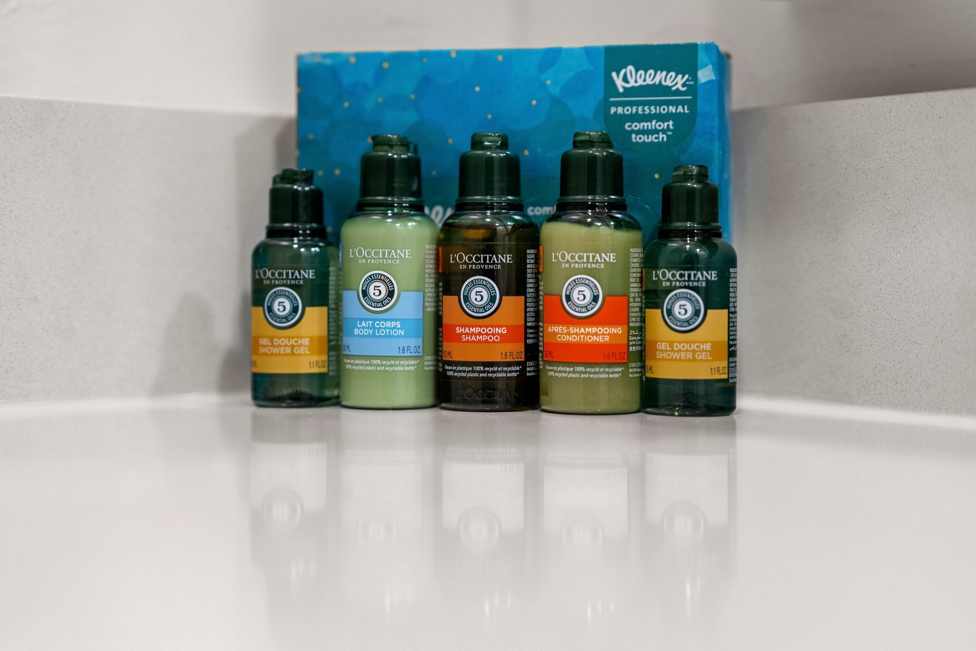 Five green and orange bottled drinks on a counter with a blue box behind them