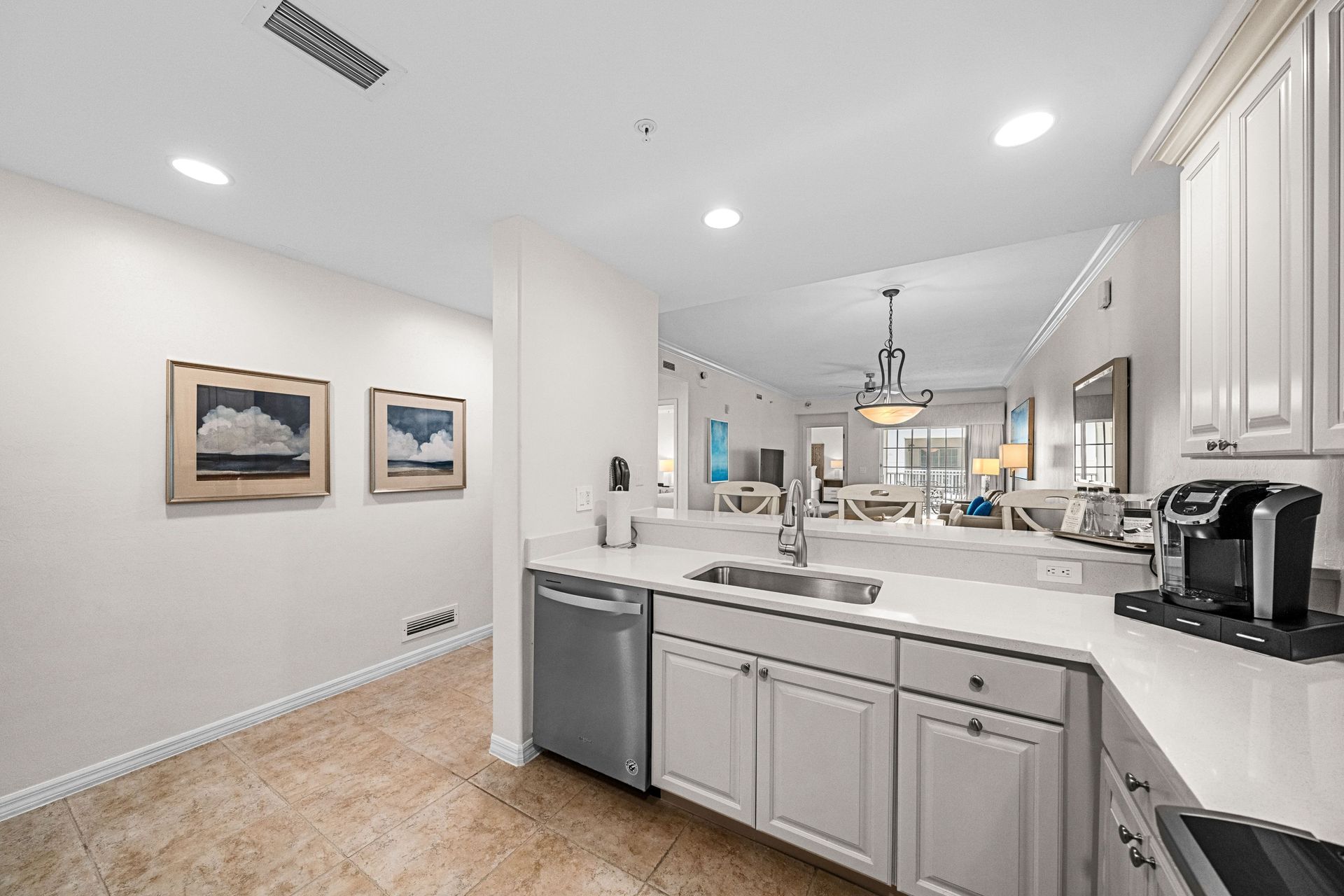 Bright modern kitchen with white cabinets, island, and stainless steel appliances in an open floor plan.