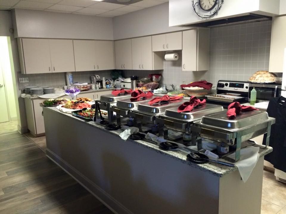 Kitchen with a buffet island holding food warming chafing dishes and prepared foods, ready for a gathering.