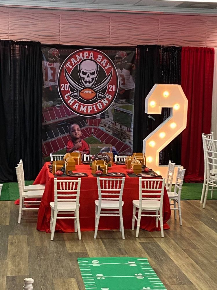 Football-themed birthday party: table set with red tablecloth, white chairs, and a lighted number 