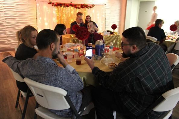 People at a table looking at a phone in a party setting with a golden backdrop.
