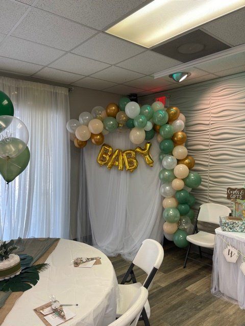 Baby shower decorated with green, gold, and white balloons, gold 